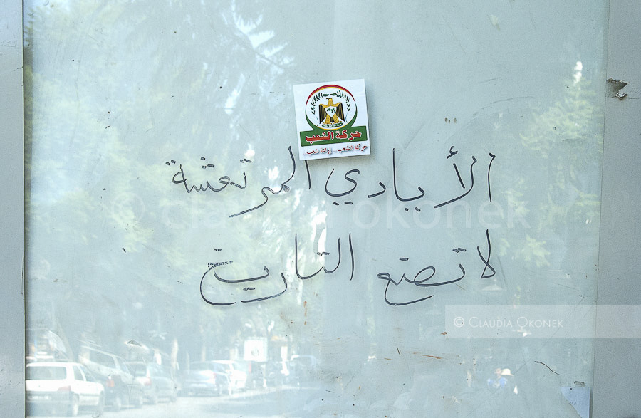 Kurz vor den Wahlen | Graffiti, `eine Hand die zittert kann keine Geschichte machen.  |  darüber ein Aufkleber  der Movement de peupl , nationalistische Partei Tunesien.
