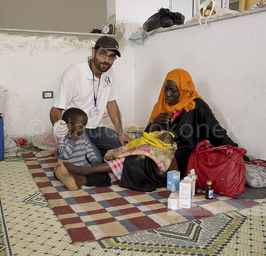 Zeitweise geduldete Hilfe durch einen Arzt  des IMC am Grenzübergang Ras Ajdir. Mutter mit Sohn und ihrem todkranken Baby. |   |  Das tunesische Militär überwacht die Transitstrasse nach Libyen , sie führt am Choucha Camp vorbei bis zum Grenzübergang Ras Ajdir. Häufig kommt es hier zu Unruhen und Blockaden durch aufgebrachte Tunesier und Libyer.